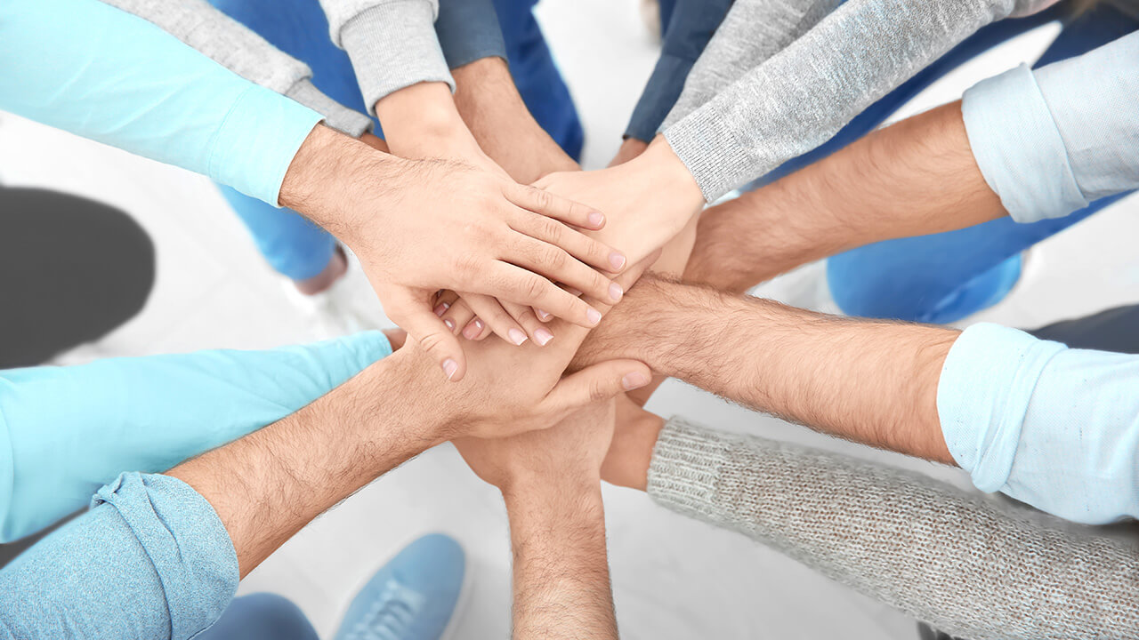 A top-down view showing multiple hands positioned in the center of the photo.