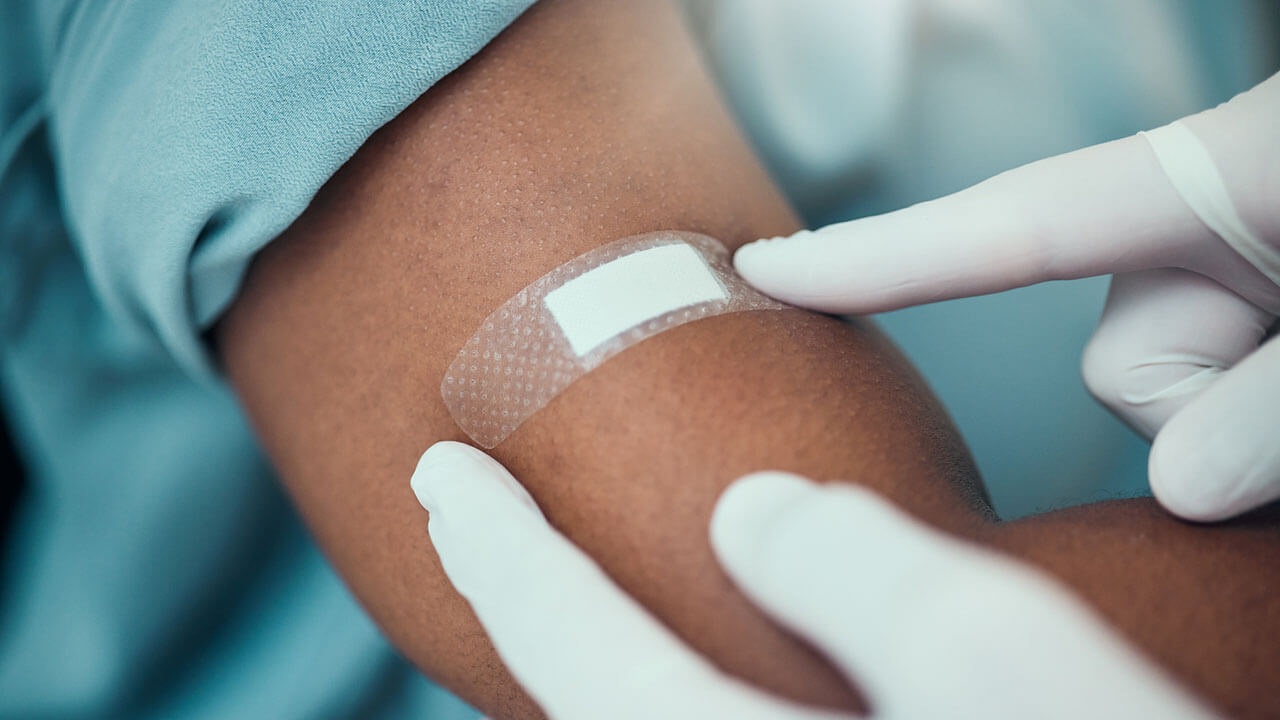 female woman getting a band aide placed on her arm from a vaccine