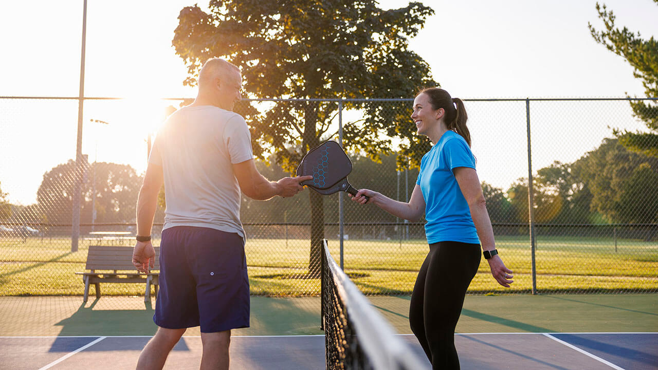 Man and woman playing pickleball outside