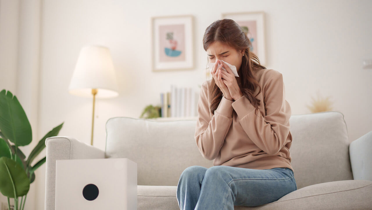 Young female blowing her nose in a living room