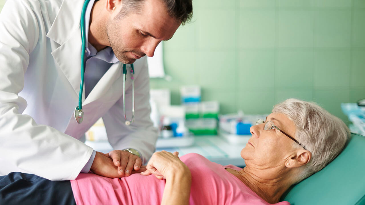 Doctor pressing down on middle aged patient's stomach