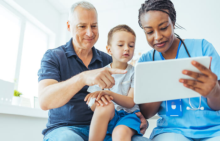 a female physician showing a father and son something on a tablet