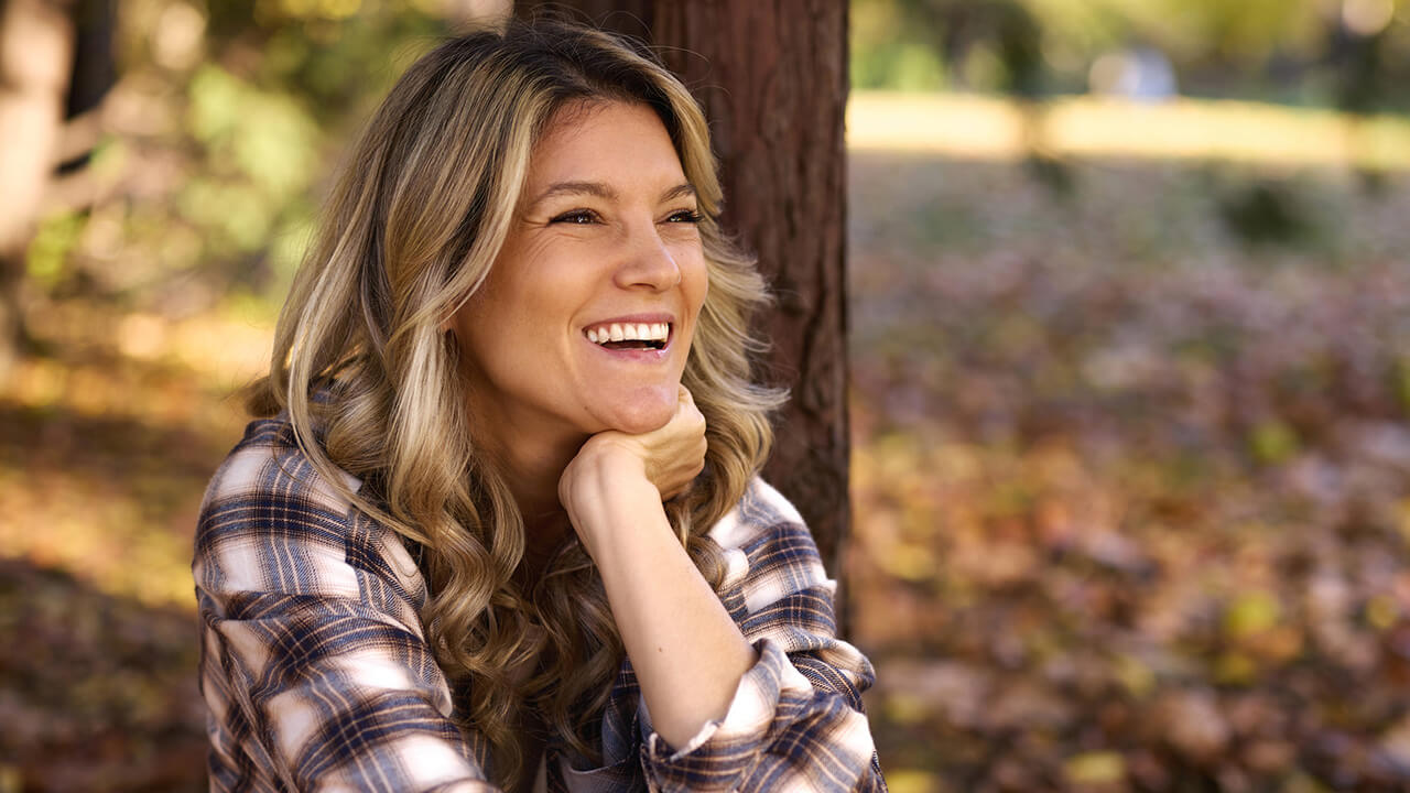 Young woman sitting outside with leaves on the ground