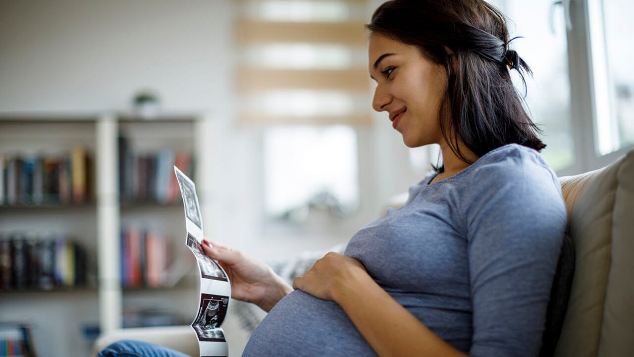 Young pregnant woman looking at ultrasound images