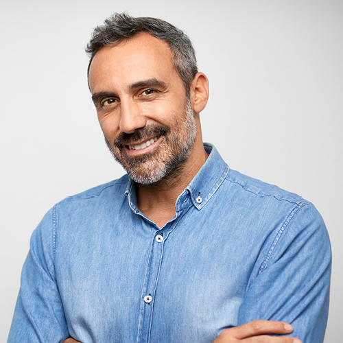man with a beard looks into camera smiling with his arms crossed