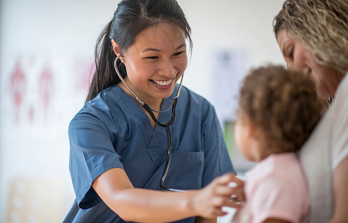 female physician checking toddler's heartbeat with stethoscope