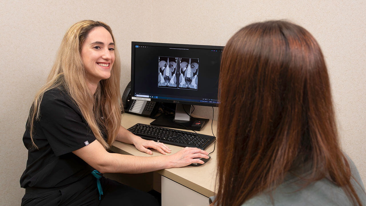 Dr. Diana Lopategui speaking with a patient in front of a computher