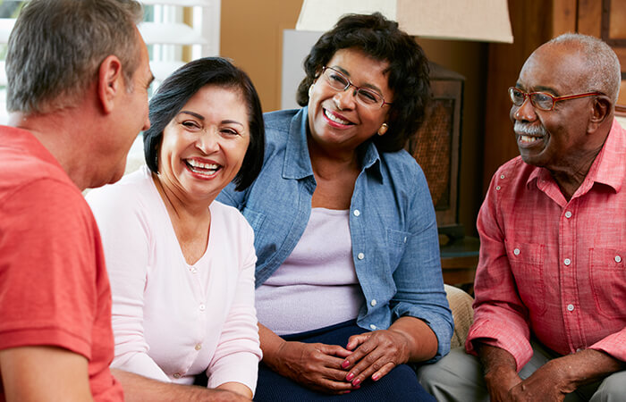 group of middle aged people sitting in a living room smiling at each other