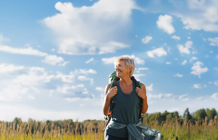 A middle aged woman hiking through long grass in the country