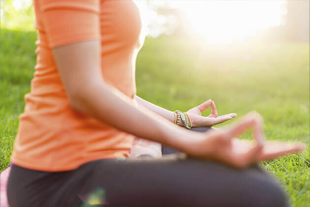 person in an orange shirt doing yoga in a park