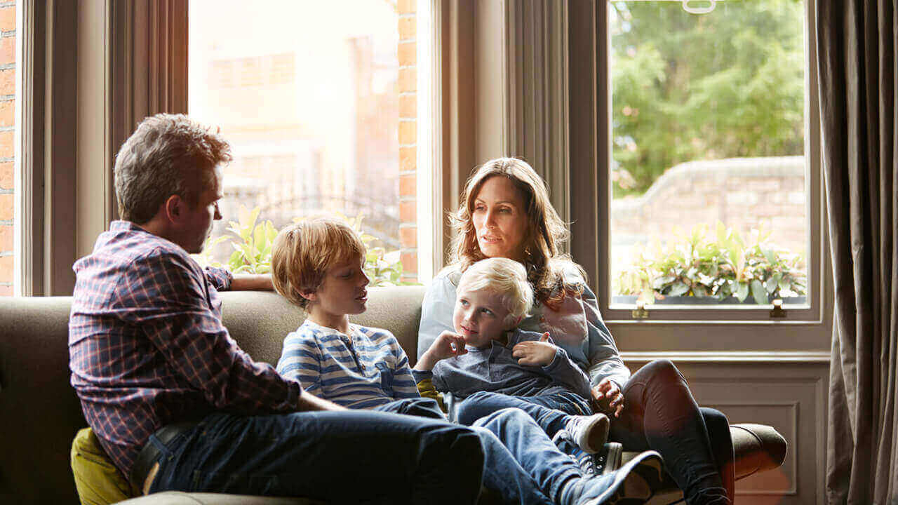 Parents sitting on a couch with two young children talking