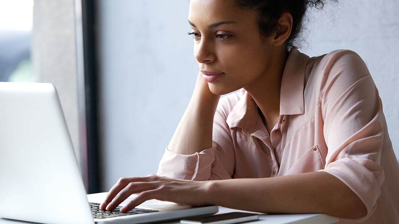 African American woman scrolling on laptop