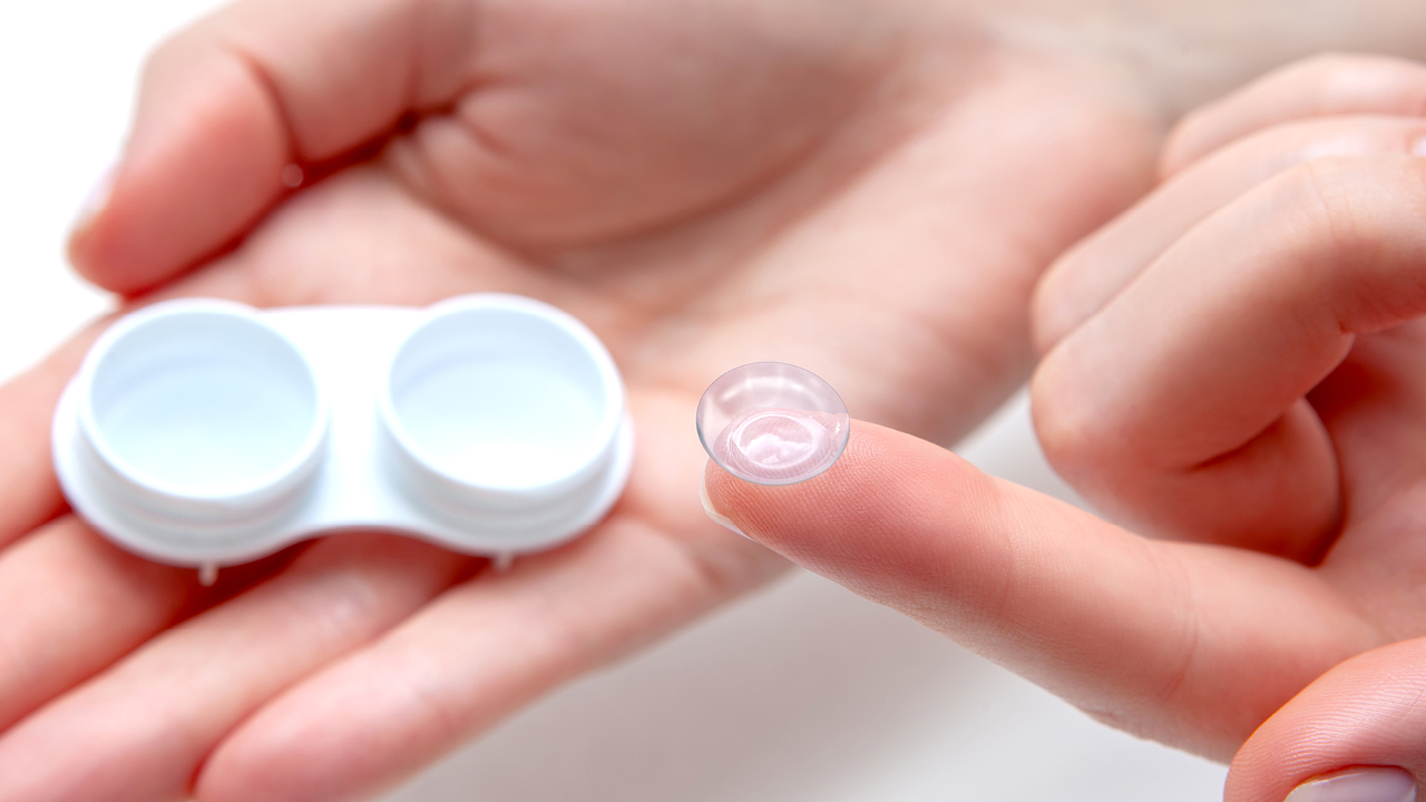 A person holding a contact case and a contact
