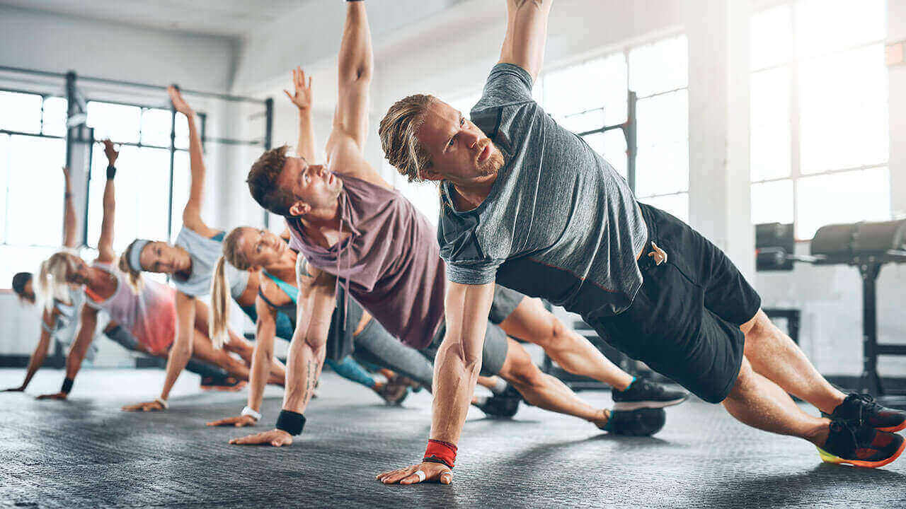 Group of men and women doing side planks at the gym