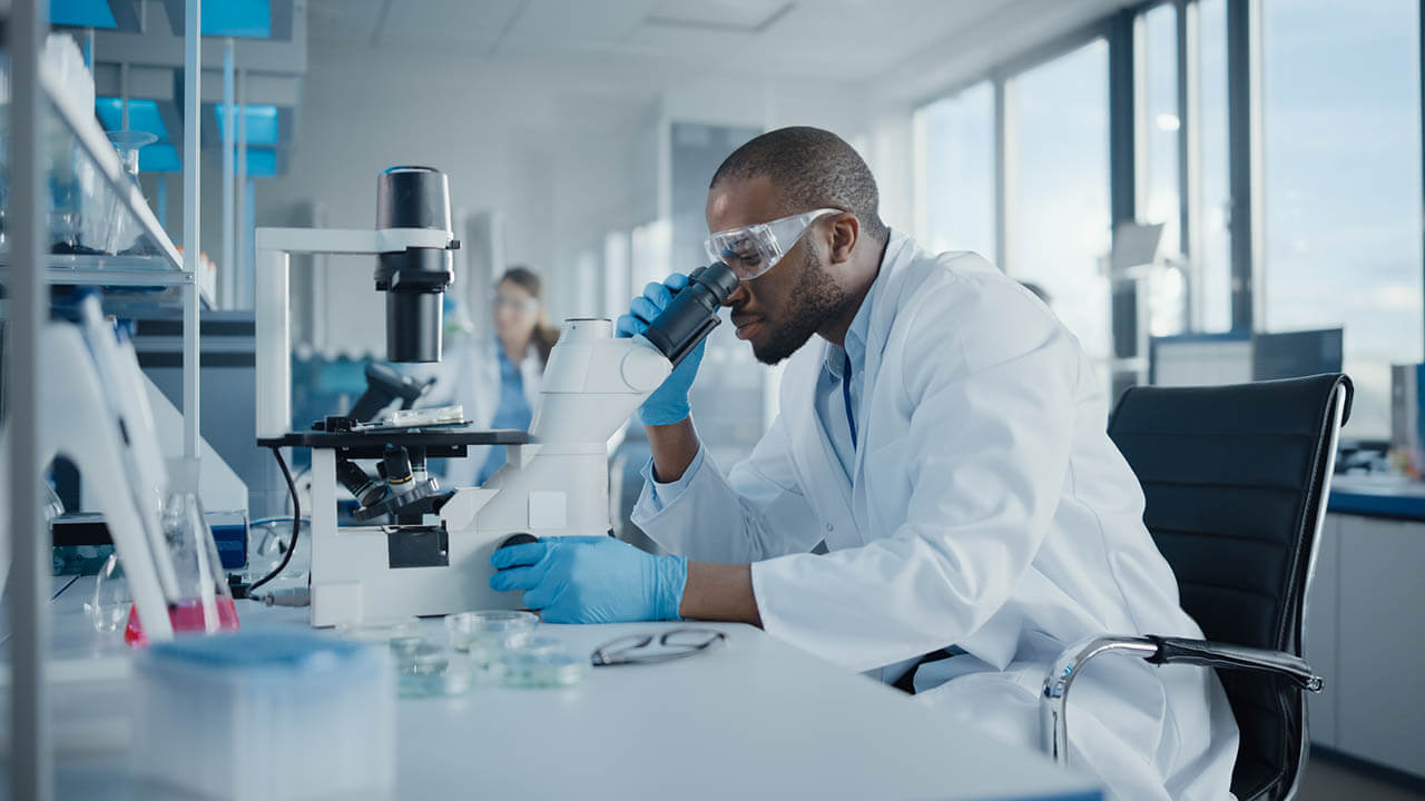 Pathologist sitting down and looking into a microscope