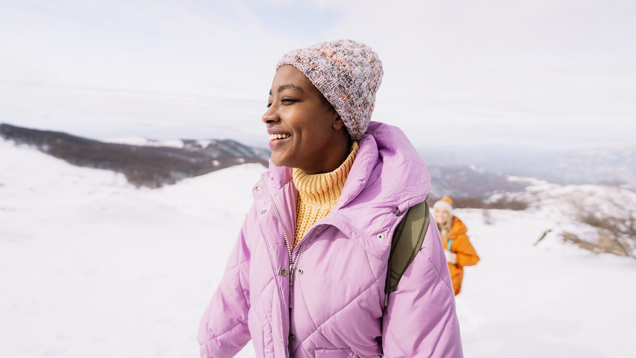 African american woman walking through the snow in a pink coat