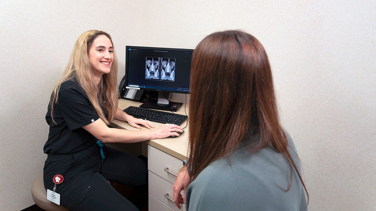 Dr. Diana Lopategui speaking with a patient in front of a computher