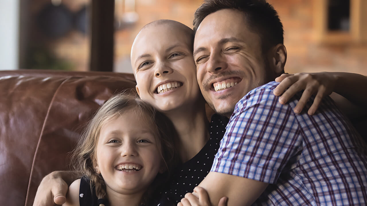 A father and his children hug while sitting on a couch