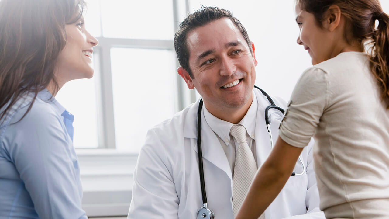 Doctor and mother smiling at young girl