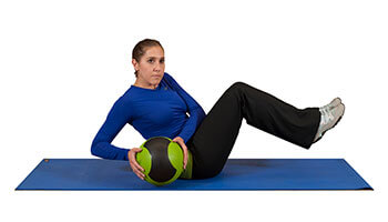 woman doing Russian twists while holding a medicine ball